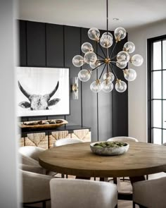 a dining room table with chairs and a chandelier hanging from it's ceiling