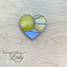 a stained glass heart sitting on top of a wooden surface with the words stained glass lady written below it