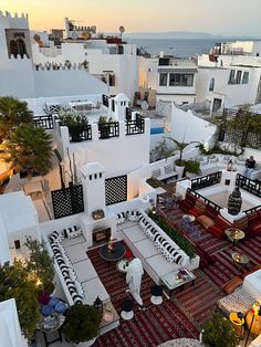 an aerial view of a patio with seating and tables on the ground, in front of white buildings