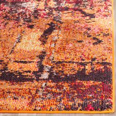 an orange, yellow and black area rug on a wooden floor with a wood floor in the background