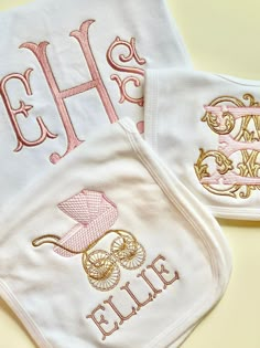 two baby bibs with embroidered monogrammed designs on them, one is pink and the other is white