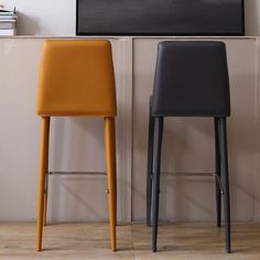 two black and yellow chairs sitting next to each other in front of a tv mounted on the wall