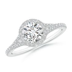 a white gold engagement ring with diamonds on the band and an oval center stone surrounded by pave