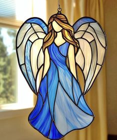 a stained glass angel ornament hanging from a window