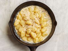 a skillet filled with macaroni and cheese on top of a white table