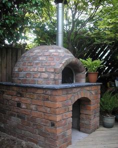 an outdoor brick pizza oven with potted plants