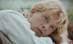 a young boy laying on the ground with his arm around an older man's shoulder