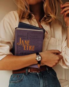 a woman is holding a book in her hands and wearing a watch on her wrist