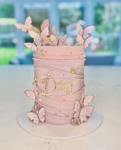 a pink cake decorated with butterflies and the word dare on it's side is sitting on a table