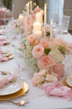 the table is set with pink and white floral centerpieces, gold chargers, silverware, and candles