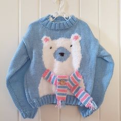 a knitted sweater with a polar bear on it hanging from a hook against a white wall