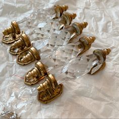 four brass and clear glass knobs on a white cloth covered table with plastic wrap around them