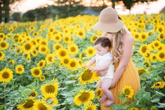 a woman holding a baby in a field of sunflowers