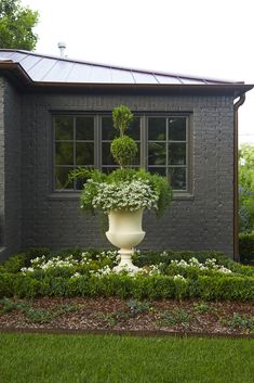 a large white vase filled with flowers in front of a house