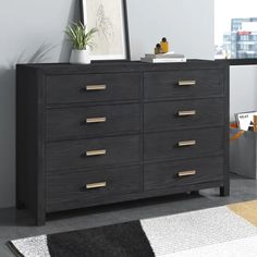 a black dresser with gold handles and drawers in a room next to a white rug