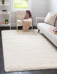 a living room with a white rug on the floor and a couch in front of it