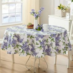 a table with purple flowers on it in front of a white dresser and window sill