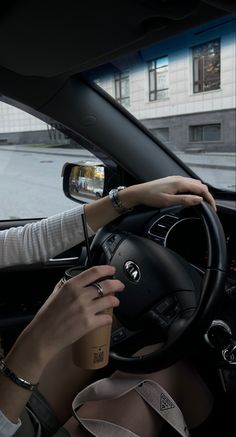 the woman is driving her car and drinking coffee