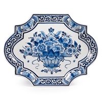 an ornate blue and white plate with flowers in a vase on the front, against a white background