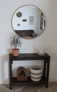 there is a mirror on the wall next to a table with a potted plant