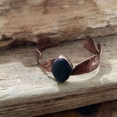 a close up of a bracelet on a piece of wood with a stone in the middle