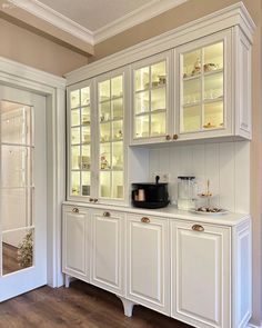 a kitchen with white cabinets and glass doors