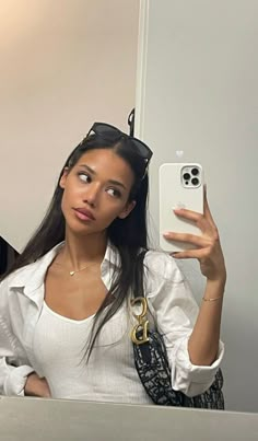 a woman taking a selfie in front of a mirror with her cell phone up to her ear