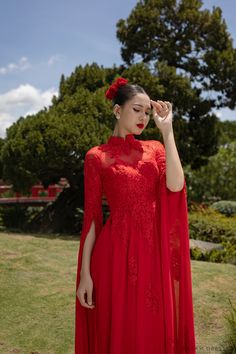 a woman in a red dress is posing for the camera with her hands on her head