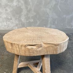 a wooden table sitting on top of a cement floor next to a gray wall,