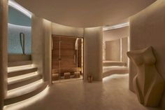 the interior of a modern spa with curved walls and stone steps leading up to an indoor sauna