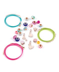 various bracelets and rings are arranged on a white surface, including one with charms