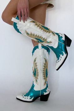 The cowgirl boots of your dreams just landed! The Azalea Wang Apolline Green Metallic Western Boot is a knee-high statement cowboy boot. Step out in style with this high-impact embroidered western boot. Featuring a white body with teal and gold metallic overlay details, and a black sole. Pair these boots with a cute mini dress for the perfect main character energy look! Details: black block heel closed pointed toe structured upper slip on design western inspired embroidery side pull tabs synthet Spring Rodeo Knee-high Boots With Snip Toe, Spring Season Rodeo Knee-high Boots With Snip Toe, Spring Knee-high Boots With Snip Toe For Rodeo, Western Knee-high Boots For Spring, Spring Wide Calf Knee-high Boots For Ranch, Western Style Wide Calf Knee-high Boots For Spring, Western Style Knee-high Boots For Rodeo, Bohemian Style Boots For Ranch In Spring, Western Wide Calf Knee-high Boots For Rodeo