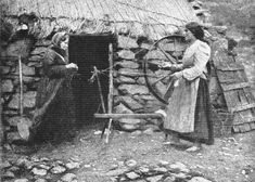 an old black and white photo of two women standing in front of a small hut