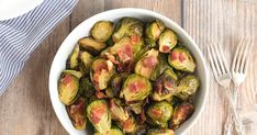 a white bowl filled with brussel sprouts on top of a wooden table