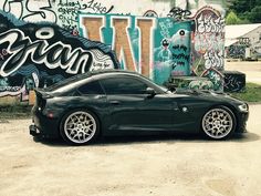 a black sports car parked in front of a graffiti covered wall with the word dream written on it