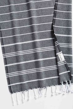 a gray and white striped towel with tassels on the ends is laying down