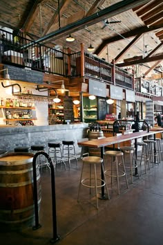 the inside of a bar with lots of stools and tables in front of it