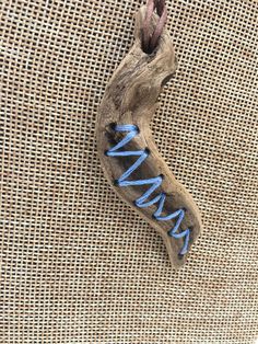 a piece of drift wood with blue writing on it sitting on a burlap surface