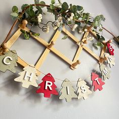 a christmas garland with wooden letters hanging from it's sides on a white wall