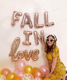 a woman sitting in front of balloons with the words fall in love