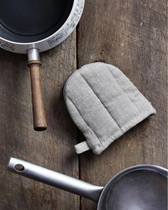 an oven mitt next to a pot and pan on a wooden table