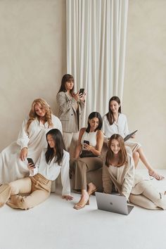 a group of women sitting next to each other in front of a window holding cell phones