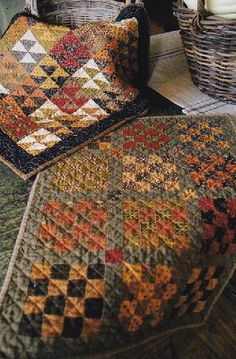 two quilts are sitting on the floor in front of a basket and table top