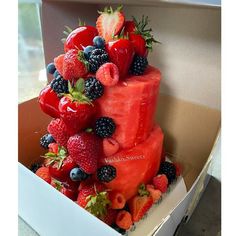 a cake made out of watermelon, strawberries and blackberries in a box