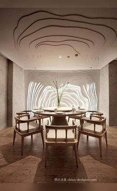 a dining room with chairs and a table in front of a large white sculpture on the wall