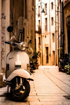 a motor scooter parked on the side of a street next to tall buildings