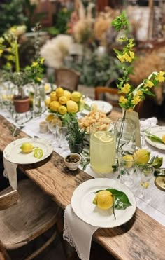 a long table is set with lemons and flowers in vases on the tables