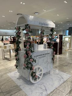 an ice cream cart decorated with flowers and greenery in a shopping mall or department store