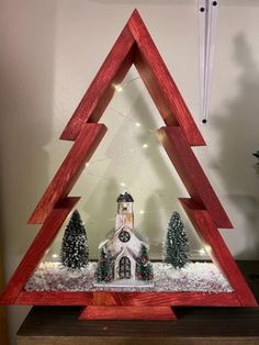 a wooden christmas tree with a church in the middle