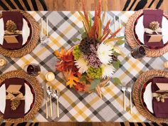 the table is set for thanksgiving dinner with plaid napkins and gold place settings on it